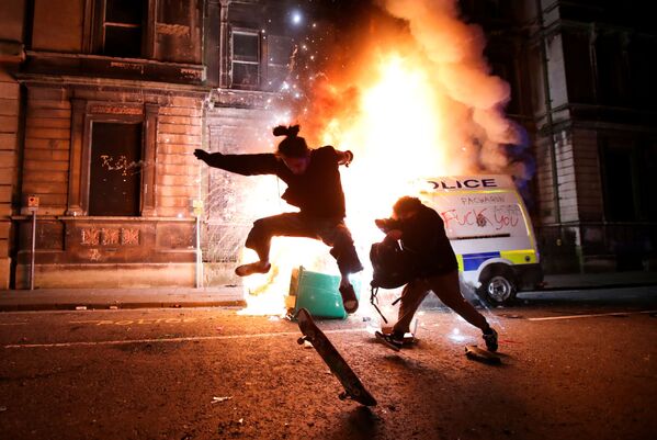 Демонстрант катается на скейтборде перед горящей полицейской машиной во время акции протеста в Бристоле, Великобритания - Sputnik Молдова