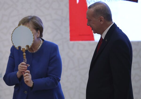 Cancelarul Germaniei, Angela Merkel. stânga, glumește când primește o oglindă prezentată de președintele Turciei Recep Tayyip Erdogan, dreapta, în timpul ceremoniei de deschidere a noului campus al unei universități turco-germane, la Istanbul, vineri, 24 ianuarie 2020. Merkel se întâlnește cu Erdogan pentru discuții care vor avea loc se așteaptă să se concentreze asupra viitorului unui acord de migrație între Turcia și UE care a contribuit la scăderea fluxurilor de refugiați către Europa. - Sputnik Moldova-România