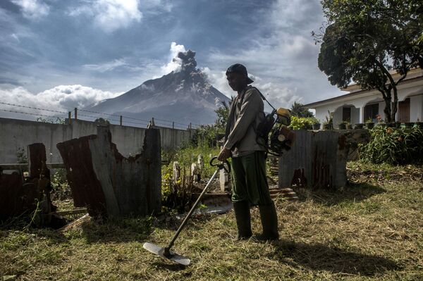 Местный житель во дворе своего дома у подножия вулкана Синабунг в Индонезии - Sputnik Молдова
