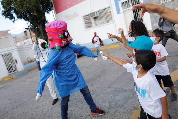 Дети прыскают алкоголем и антицептиком на человека в костюме коронавируса в Венесуэле   - Sputnik Moldova