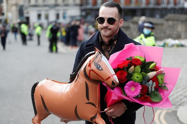 Мужчина несет надувную лошадь и цветы в память об умершем принце Филиппе - Sputnik Молдова