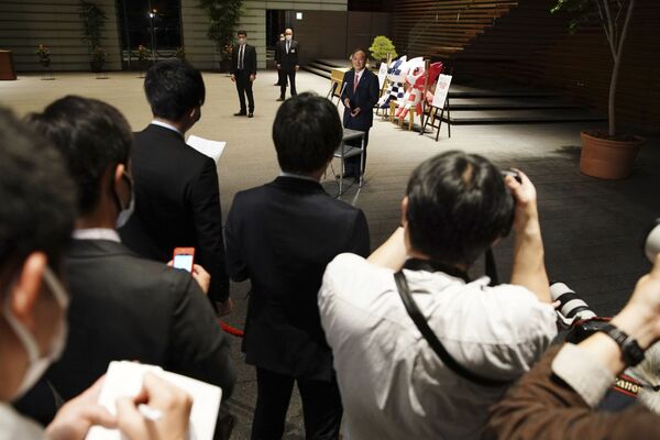 Премьер-министр Японии Есихидэ Суга на пресс-конференции с талисманами Летней Олимпиады сзади в Токио  - Sputnik Молдова