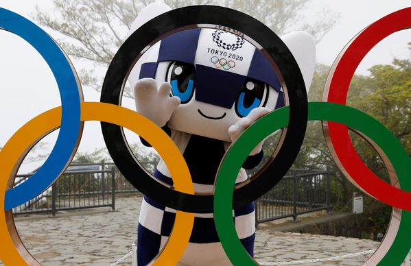 Талисман Летней Олимпиады в Токио Miraitowa позирует сзади Олимпийских колец после мероприятия по случаю 100 дней до Олийписких игр в Токио  - Sputnik Молдова