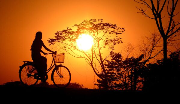 Индийская девушка катается на велосипеде во время заката в деревне Джойпур - Sputnik Молдова