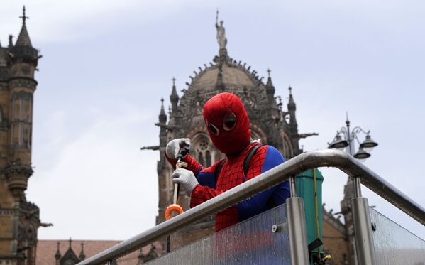 Социальный работник Ашок Курми в костюме человека-паука дезинфицирует перила у железнодорожной станции Chhatrapati Shivaji Maharaj Terminus в Мумбаи, Индия - Sputnik Молдова