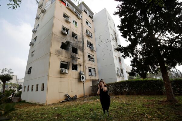 Женщина возле жилого дома, поврежденного после попадания в него ракеты, запущенной из сектора Газа, в Ашкелоне - Sputnik Moldova-România