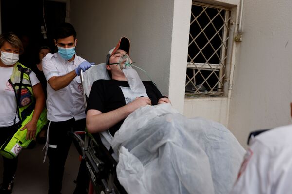 Израильские медики эвакуируют человека, получившего ранение в результате попадания ракеты из сектора Газа в жилой дом в Ашкелоне, на юге Израиля - Sputnik Moldova-România