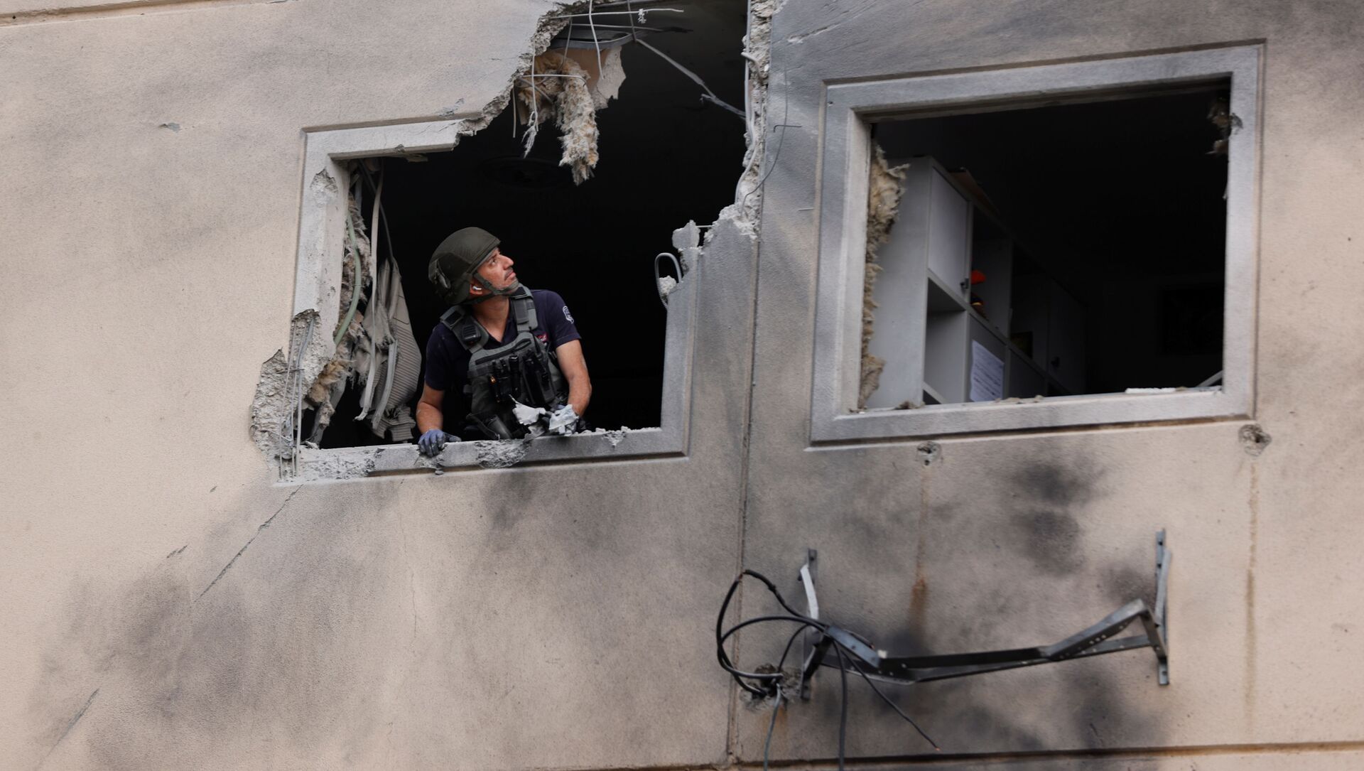 Эксперт по обезвреживанию бомб израильской полиции смотрит из окна жилого дома, который был поврежден после попадания в него ракеты, запущенной из сектора Газа, в Ашкелоне - Sputnik Moldova-România, 1920, 14.05.2021
