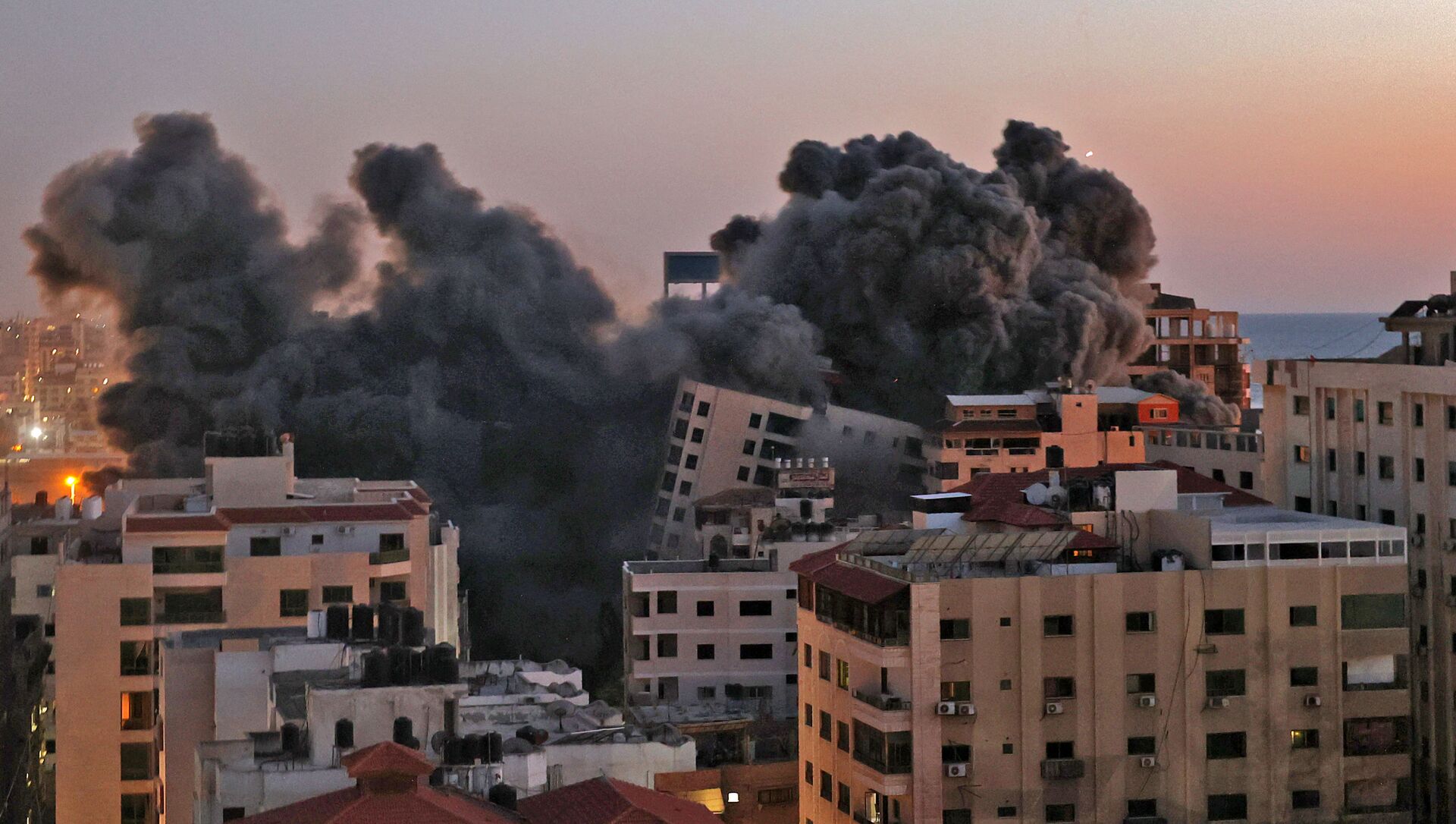 Пожарные тушат горящие многоквартирные дома после израильских авиаударов в городе Газа - Sputnik Молдова, 1920, 12.05.2021