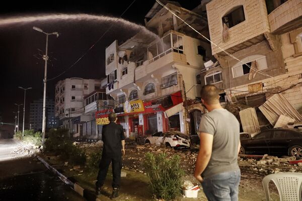 Pompierii sting clădirile rezidențiale care ard, după ce au fost lovite de atacurile aeriene israeliene în orașul Gaza. - Sputnik Moldova-România