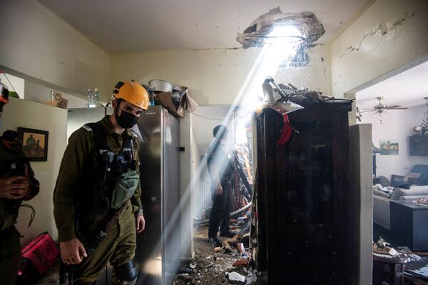Soldații lucrează în afara unei clădiri avariate de o rachetă lansată din Fâșia Gaza din Ashdod, sudul Israelului. - Sputnik Moldova-România