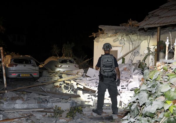 Un ofițer de securitate israelian examinează pagubele unei case din Yehuda, lângă Tel Aviv. - Sputnik Moldova-România