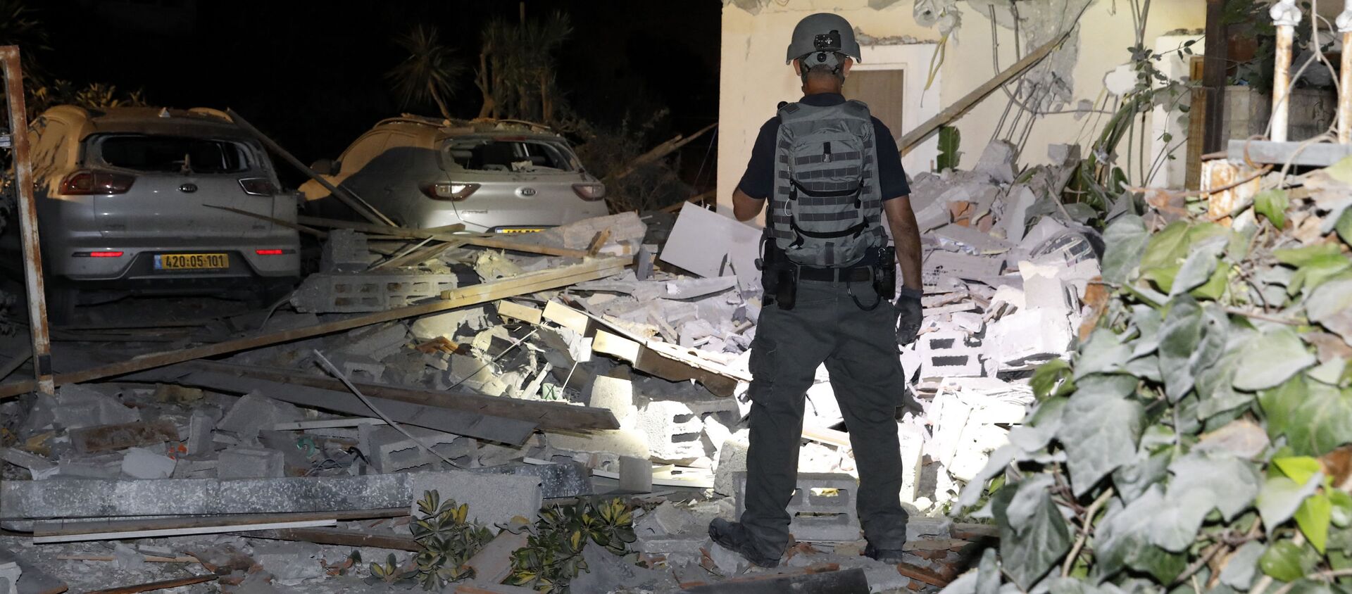 Офицер службы безопасности Израиля осматривает повреждения дома в Йехуде, недалеко от Тель-Авива - Sputnik Молдова, 1920, 14.05.2021