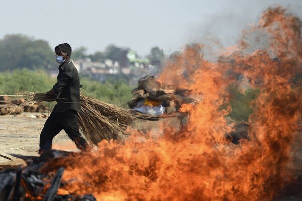 Рабочий проходит мимо горящего погребального костра человека, умершего из-за коронавируса Covid-19, Индия  - Sputnik Молдова