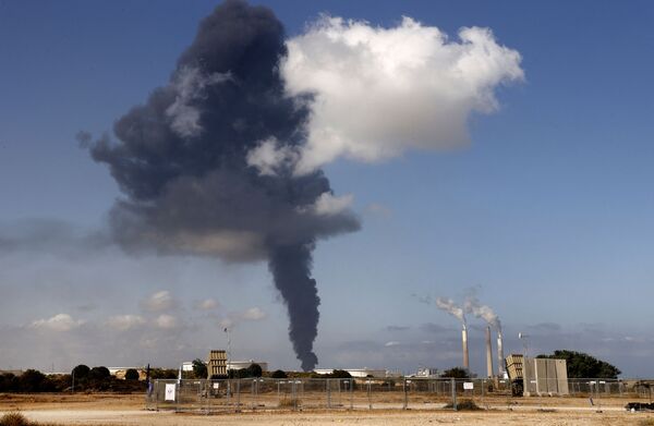 Шлейф дыма от бушующего пожара на нефтехимическом складе вздымается на нефтехранилище, пораженном ракетами ХАМАС в городе Ашкелон - Sputnik Молдова