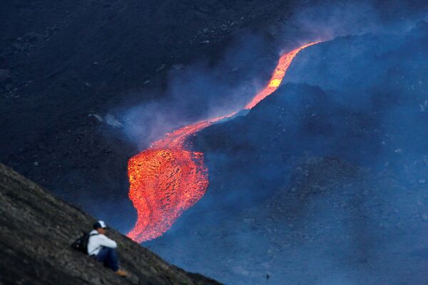 Мужчина наблюдает за течением раскаленной лавы вулкана Пакая в регионе Эскуинтла, Гватемала - Sputnik Молдова