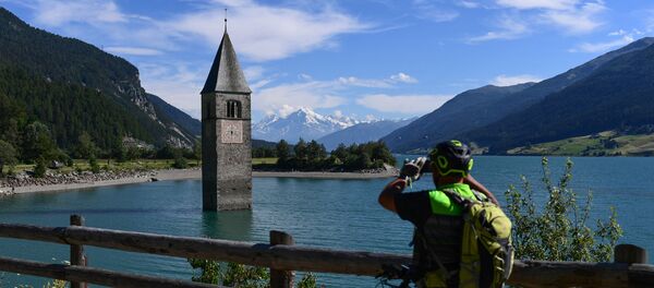 Велосипедист, фотографирует колокольню старой городской церкви Курона Велосипедист, фотографирует колокольню старой городской церкви Курона - Sputnik Молдова