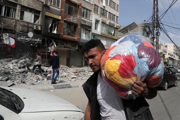 Un palestinian trece prin prejudiciile provocate de atacul aerian israelian în Fâșia Gaza - Sputnik Moldova-România