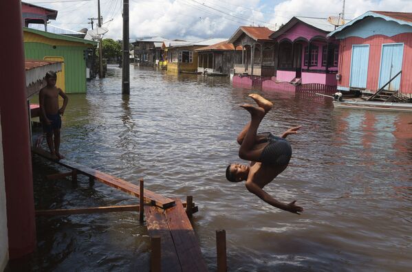 Мальчик прыгает в воду на затопленной улице в Анаме, штат Амазонас, Бразилия - Sputnik Молдова