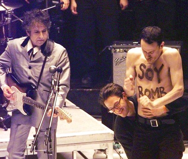 Демонстрант с надписью «Соевая бомба» уходит со сцены, когда Боб Дилан исполняет песню из своего альбома - Sputnik Молдова