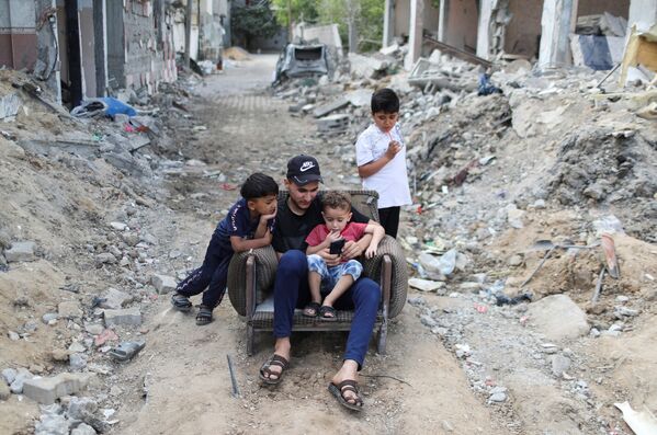 Палестинцы сидят на территории разрушенных домов в результате бомбардировки в секторе Газа - Sputnik Moldova