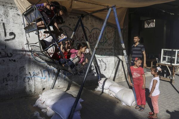 Палестинец наблюдает за детьми, играющими на качелях в разрушенном районе на севере сектора Газа - Sputnik Moldova