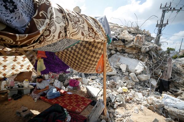 Un palestinian pe teritoriul unei case distruse în urma unui bombardament din Fâșia Gaza - Sputnik Moldova-România