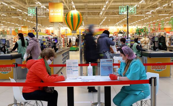 Женщина заполняет документы перед вакцинацией от COVID-19 российской вакциной Спутник V (Гам-КОВИД-Вак) в гипермаркете Глобус в Москве - Sputnik Молдова