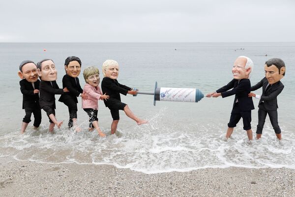Activiștii Oxfam, cu caricaturi ale liderilor mondiali în timpul unui protest pe plajă din Cornwall, Marea Britanie - Sputnik Moldova