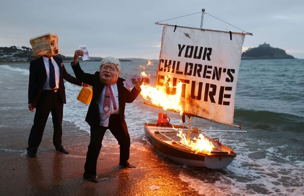 Activiștii grupului de luptă cu schimbările climatice Ocean Rebellion au dat foc unei bărci în timpul unei demonstrației pe plaja Marazion, Cornwall, Marea Britanie - Sputnik Moldova