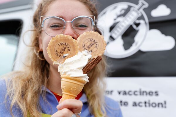 Активистка Джесс Мидвинтер держит мороженое с печеньем с посланием, призывающим к отказу от интеллектуальной собственности на вакцины. - Sputnik Молдова
