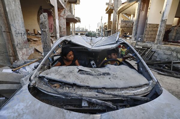Copiii palestinieni se joacă într-o mașină distrusă în timpul conflictului dintre Hamas și Israel. - Sputnik Moldova-România