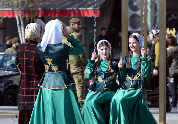 Девушки катаются на качелях на площади в Грозном на праздновании Дня народного единства. - Sputnik Молдова