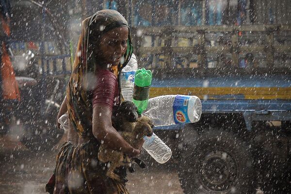 Женщина ищет убежища во время ливня в Дакке. - Sputnik Молдова