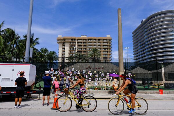 Люди у стены с фотографиями жителей разрушенного здания в Майами. - Sputnik Молдова