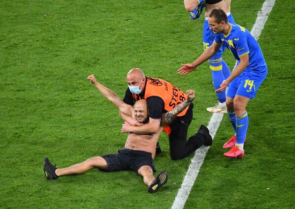 Persoane din serviciul de pază cu un bărbat care a fugit pe teren în timpul meciului Suedia-Ucraina de la UEFA EURO 2020 - Sputnik Moldova-România