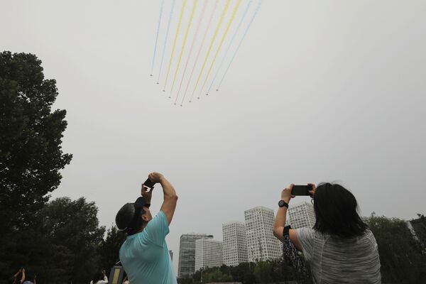 Oamenii își țin telefoanele mobile în timp ce avioanele militare zboară în formație în timpul sărbătorii care marchează 10 de ani de la fondatoare a Partidului Comunist din China, într-un parc din Beijing, China, 1 iulie 2021. - Sputnik Moldova-România