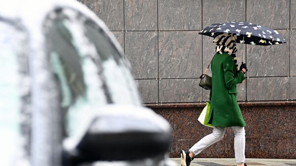 Девушка идет под зонтом во время снегопада на одной из улиц Москвы. - Sputnik Молдова