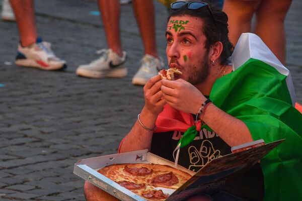 Un fan italian mănâncă pizza în zona fanilor din Piazza del Popolo din Roma. - Sputnik Moldova-România