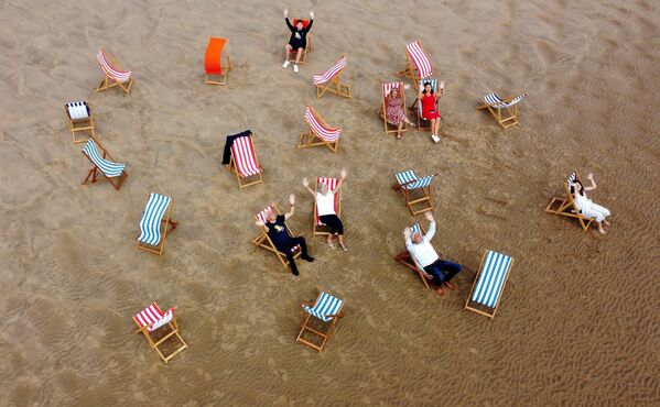 Люди позируют для фотографии, сидя в шезлонгах на пляже в Блэкпуле, Великобритания - Sputnik Молдова