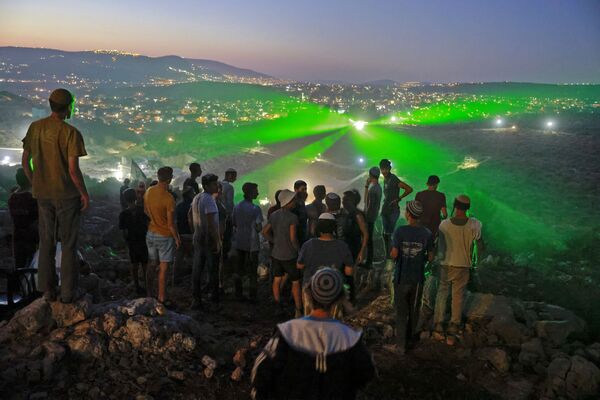 Израильские поселенцы на аванпосте Эвиатар смотрят, как палестинские протестующие направляют на них лазерные лучи из близлежащей деревни Бейта - Sputnik Молдова