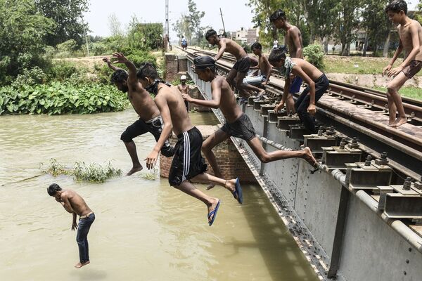 Подростки прыгают в канал, чтобы освежиться в жаркий летний день на окраине Амритсара, Индия - Sputnik Молдова