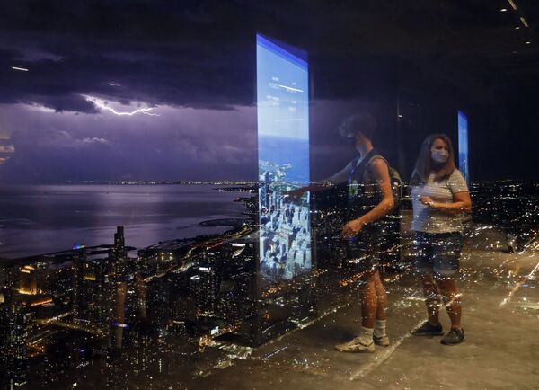Люди отражаются на стеклянной стене Уиллис-Тауэр в Чикаго на фоне молний над озером Мичиган - Sputnik Молдова