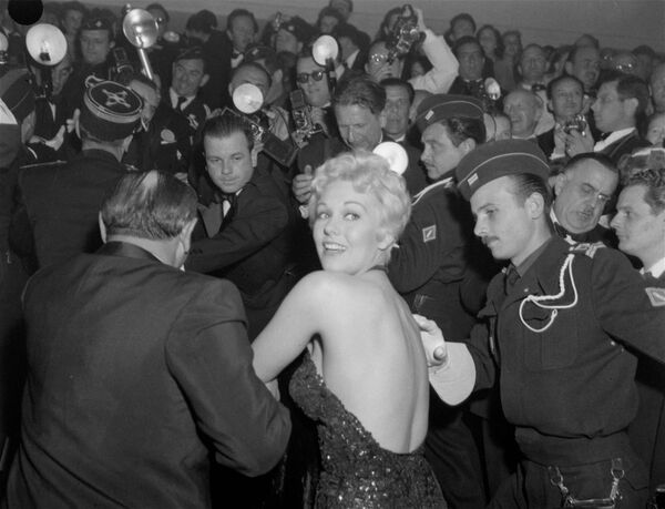 Актриса Ким Новак проталкивается сквозь толпу репортеров на вечернее представление Каннского кинофестиваля, 1956 год. - Sputnik Молдова