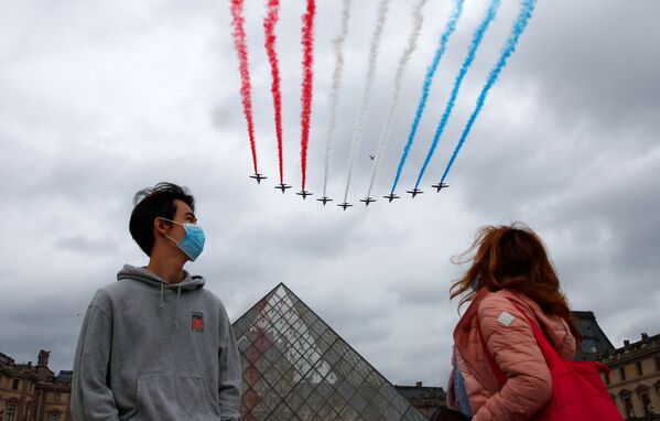 Зрители в защитных масках наблюдают, как реактивные самолеты Alpha из французских ВВС Patrouille de France пролетают мимо Пирамиды Лувра. - Sputnik Молдова