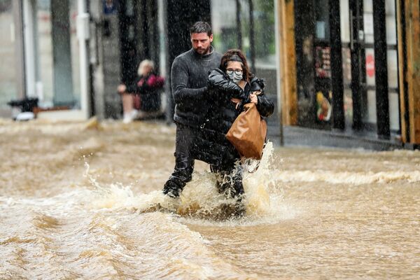 Un bărbat ajută o femeie să meargă pe o stradă inundată din Spa, Belgia. - Sputnik Moldova