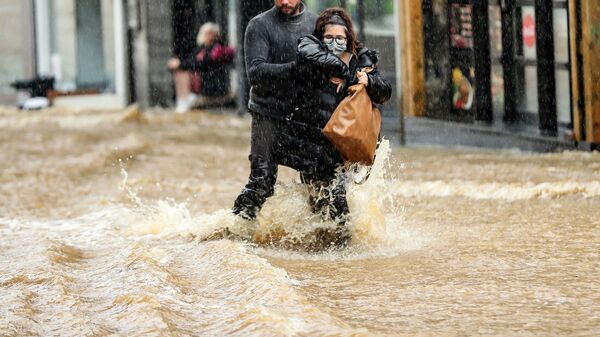 Мужчина помогает женщине пройтись по затопленной улице в городе Спа, Бельгия - Sputnik Moldova