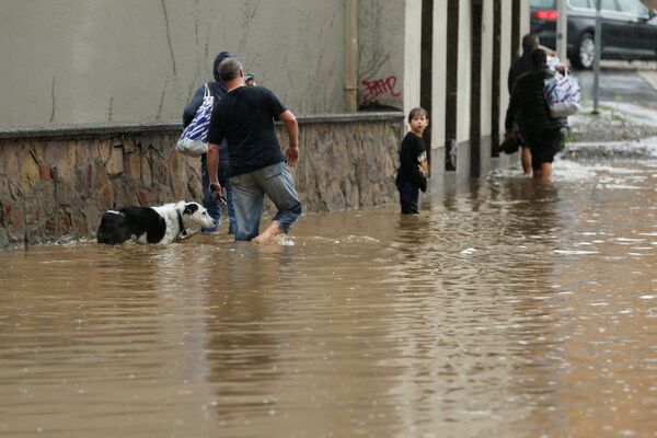 Люди идут по затопленной улице после проливных дождей в Хагене, Германия. - Sputnik Молдова