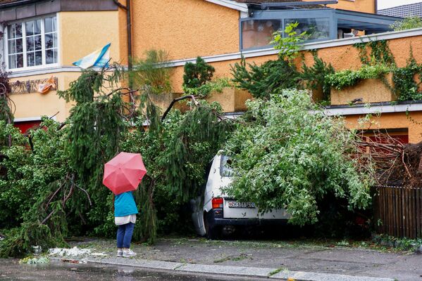 O femeie n fața unei camionete avariate de un copac căzut în timpul furtunii în Zurich, Elveția. - Sputnik Moldova