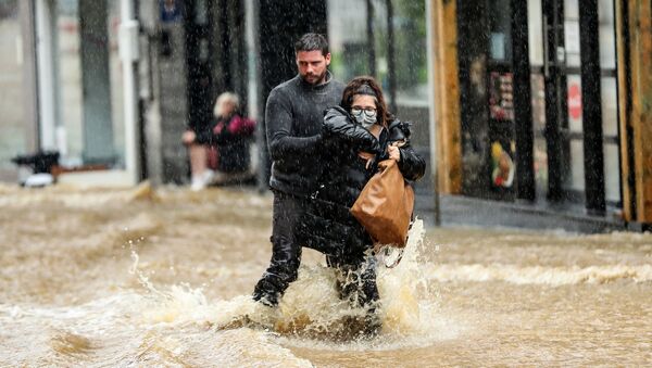 Мужчина помогает женщине пройтись по затопленной улице в городе Спа, Бельгия - Sputnik Moldova-România